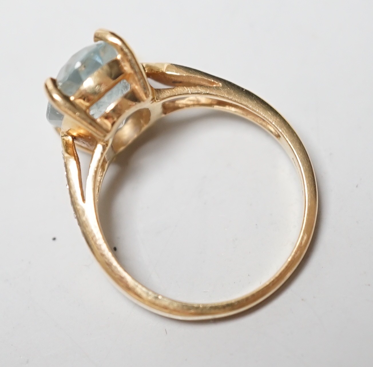 A modern 18ct gold and oval cut aquamarine set dress ring, with diamond chip set shoulders, size N, gross weight 5.5 grams.